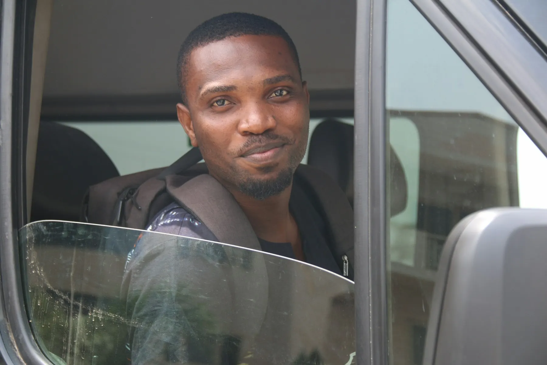 A smiling driver looking out of his vehicle window
