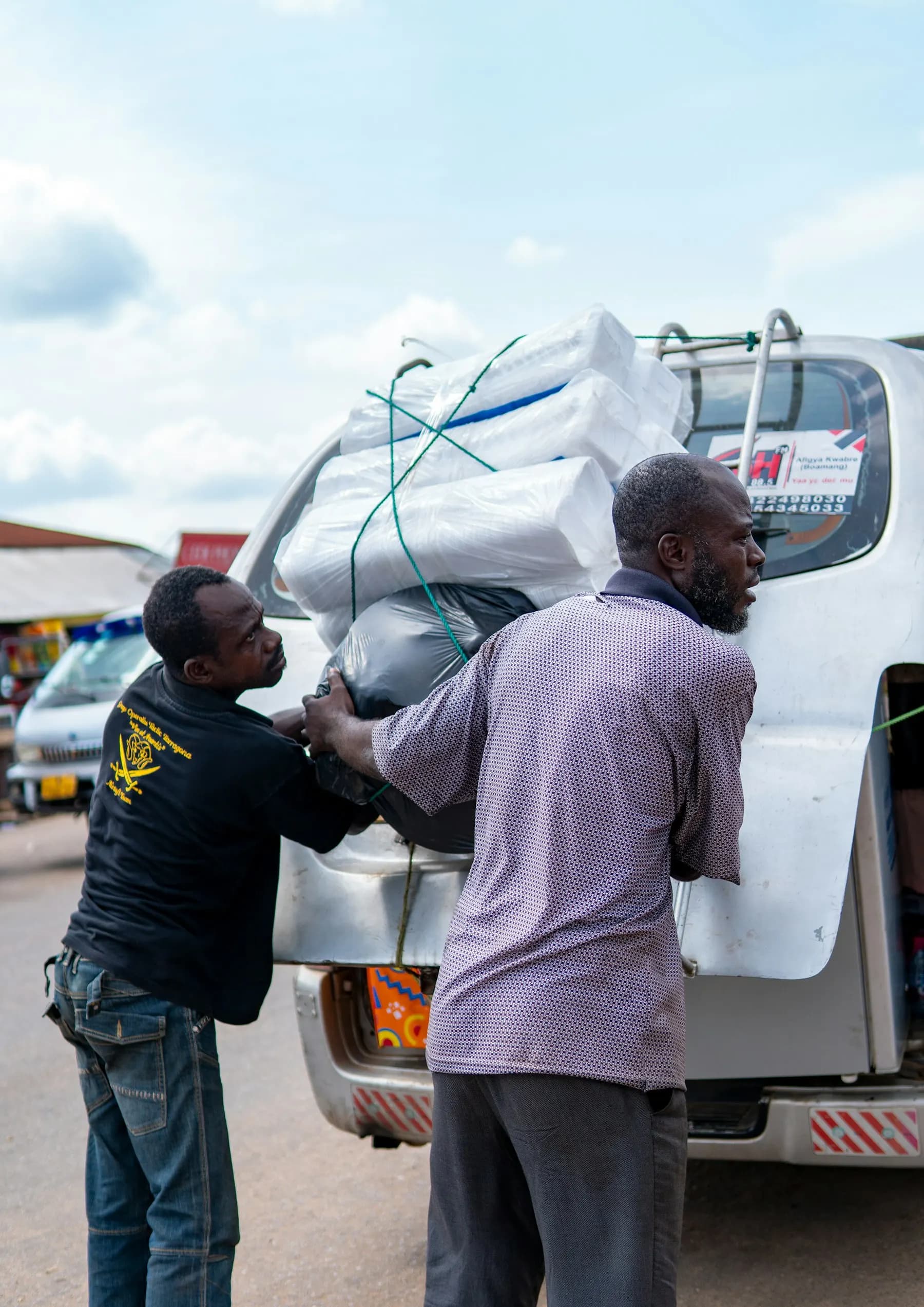 Two men loading parcels onto the roof of a van