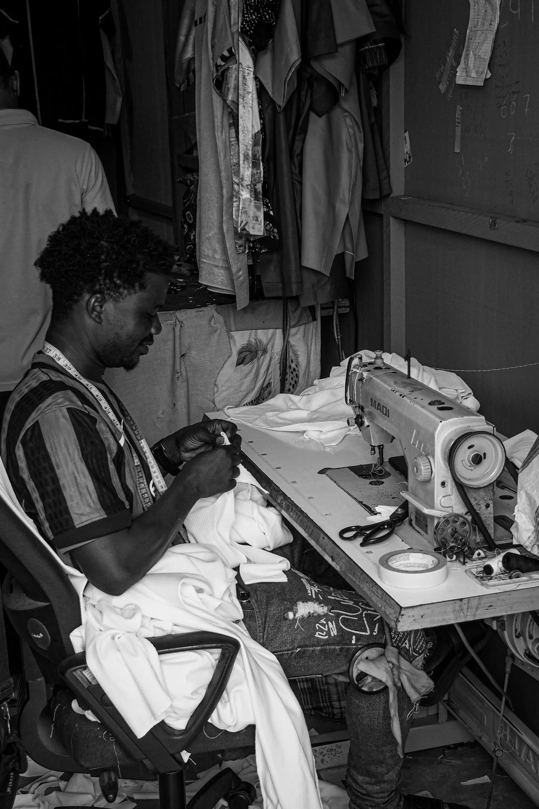 A tailor at a sewing machine in a clothing shop