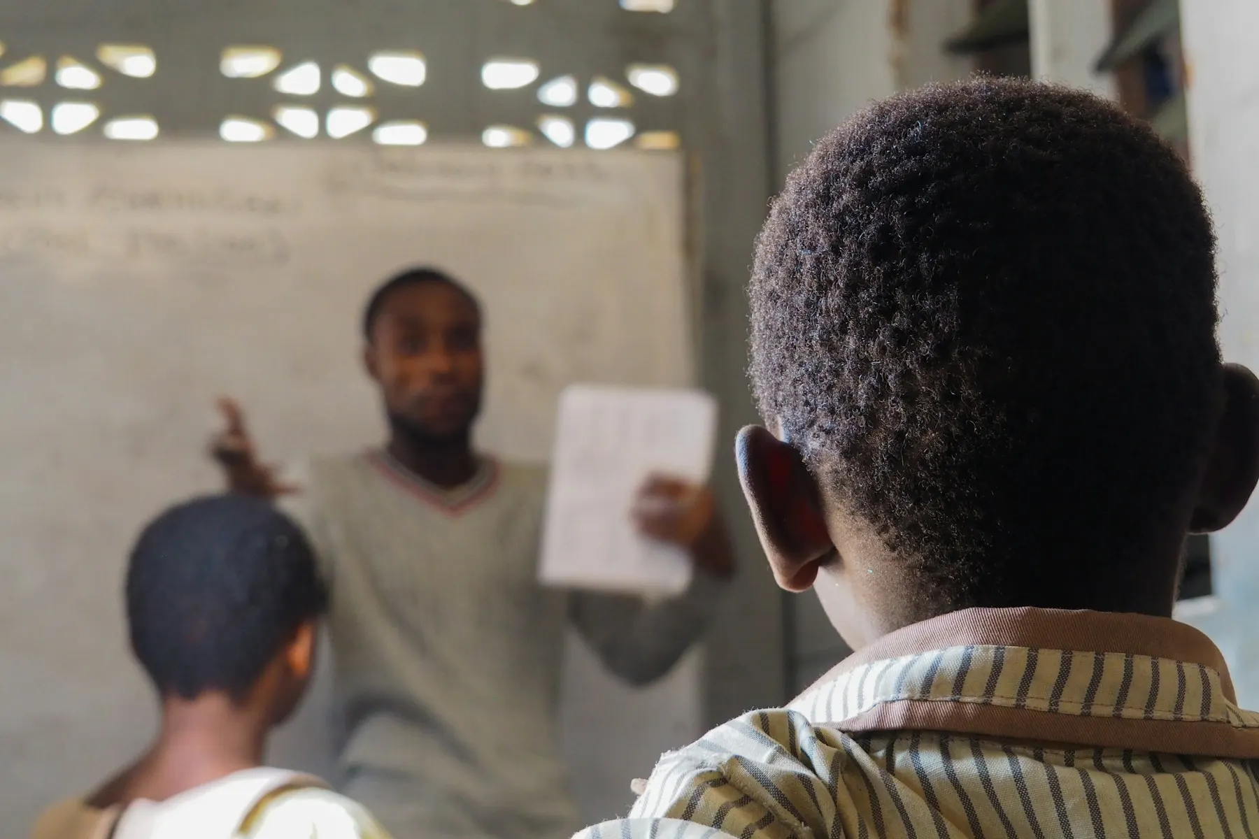 A teacher holding up a notebook in front of a class