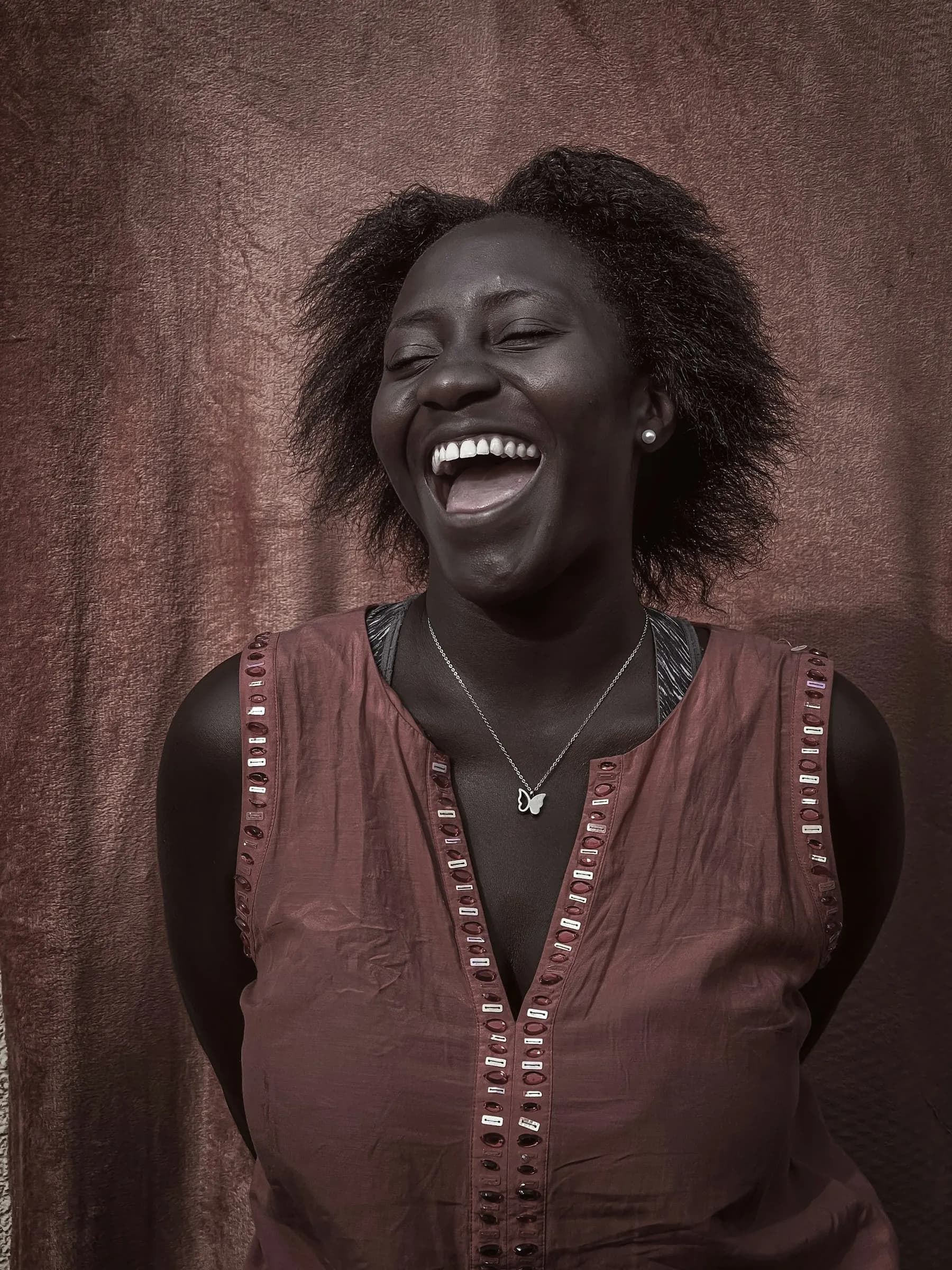 A woman laughing, photographed in a studio